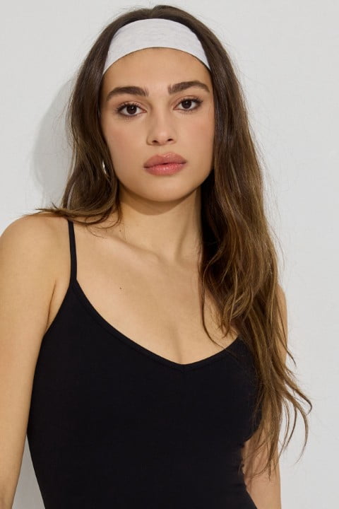 Model wears a white headhand and black tank top.