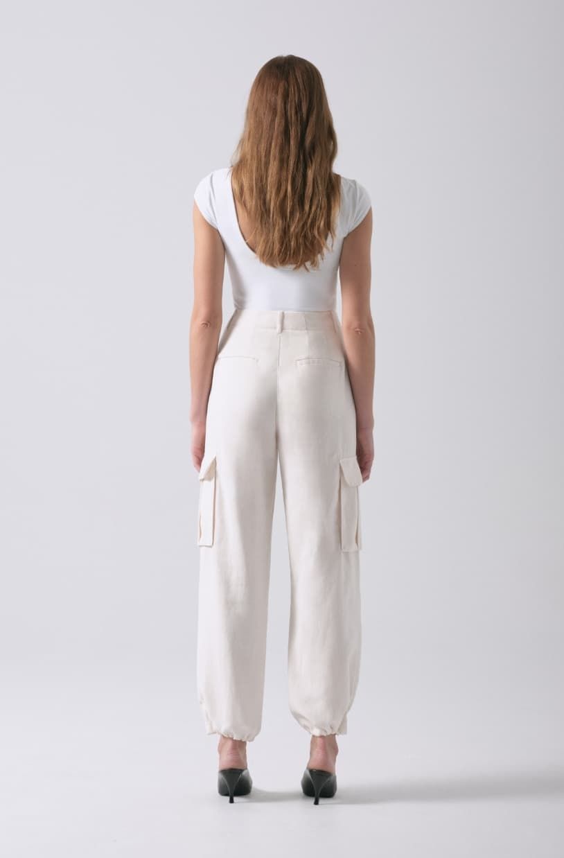 A model wears white cargo parachute pants with a white t-shirt.