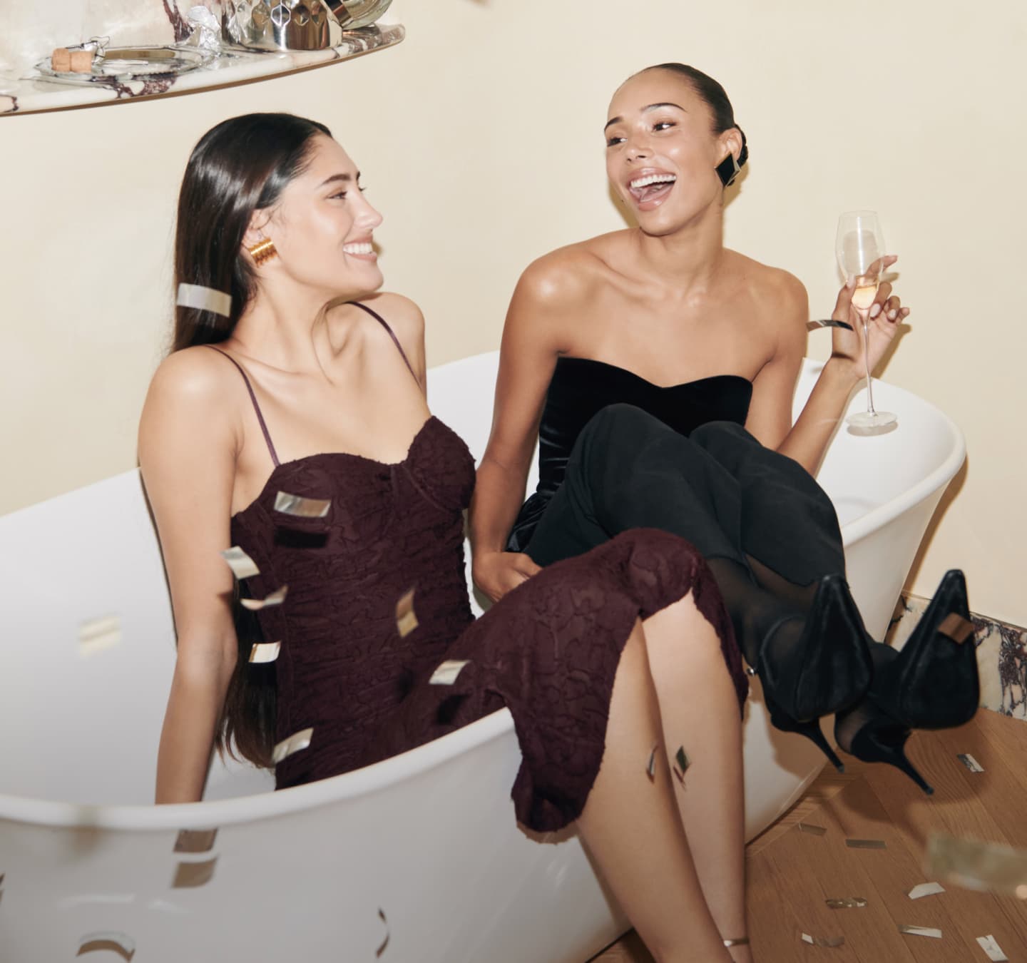 Model on the right is wearing a brown maxi dress. Model on the left is wearing a white satin shirt and white skirt.