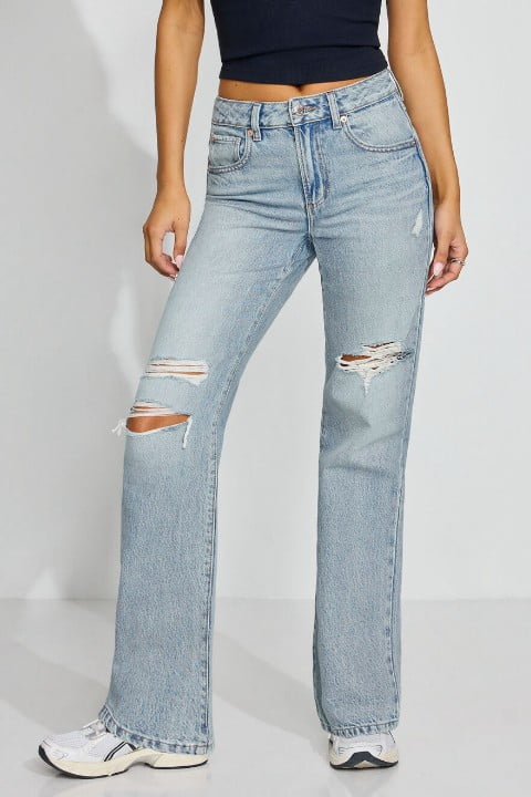 Model wears a black tank top and distressed light wash jeans.