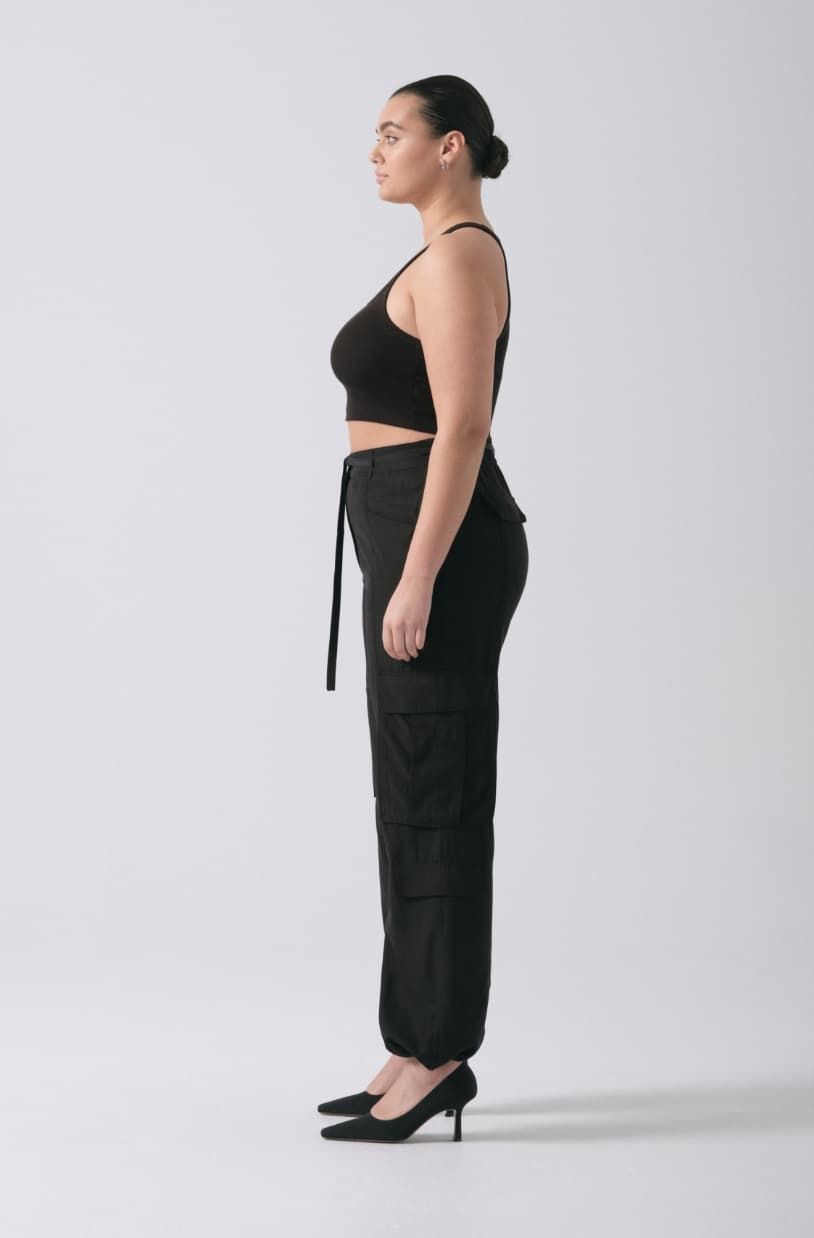 A model wears black cargo pants with a black tank top.