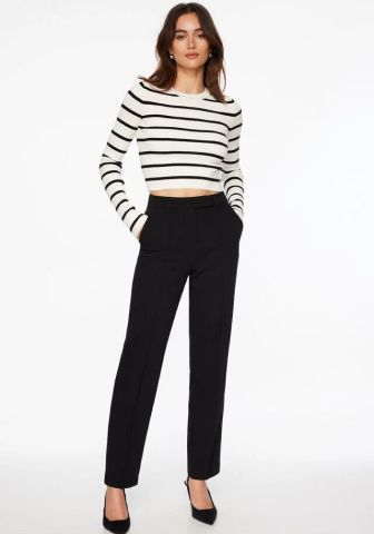 Model is wearing a white striped sweater and black pants.