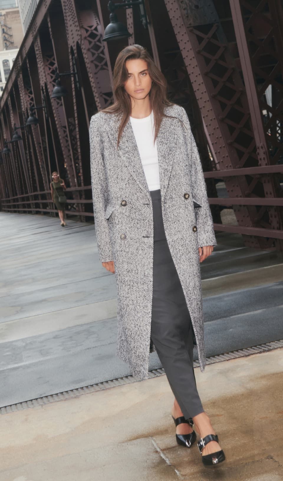A model wears a grey trench coat with a grey pencil skirt and white top.
