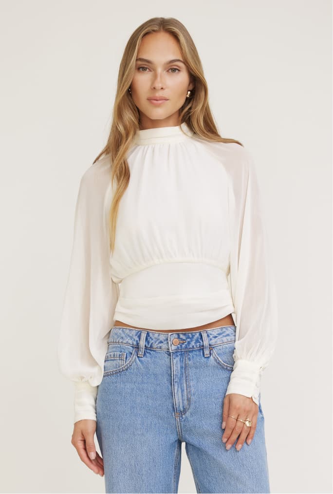 Model is wearing a white chiffon blouse with light blue jeans.