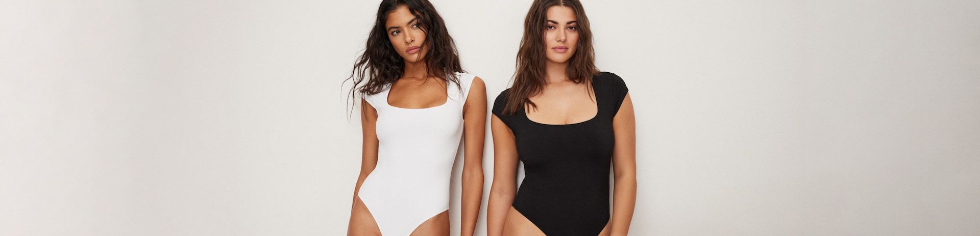 One model wears a white short sleeve sculpt bodysuit and another model wears the same bodysuit in black.