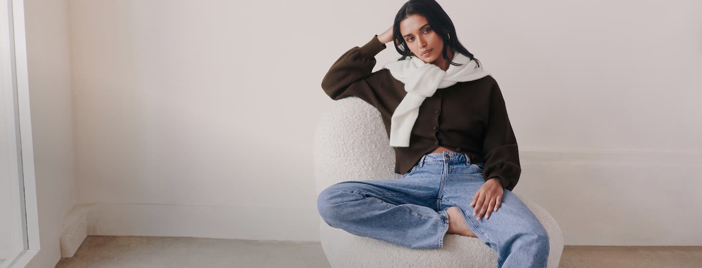 Model is wearing a brown cardigan and light blue jeans.