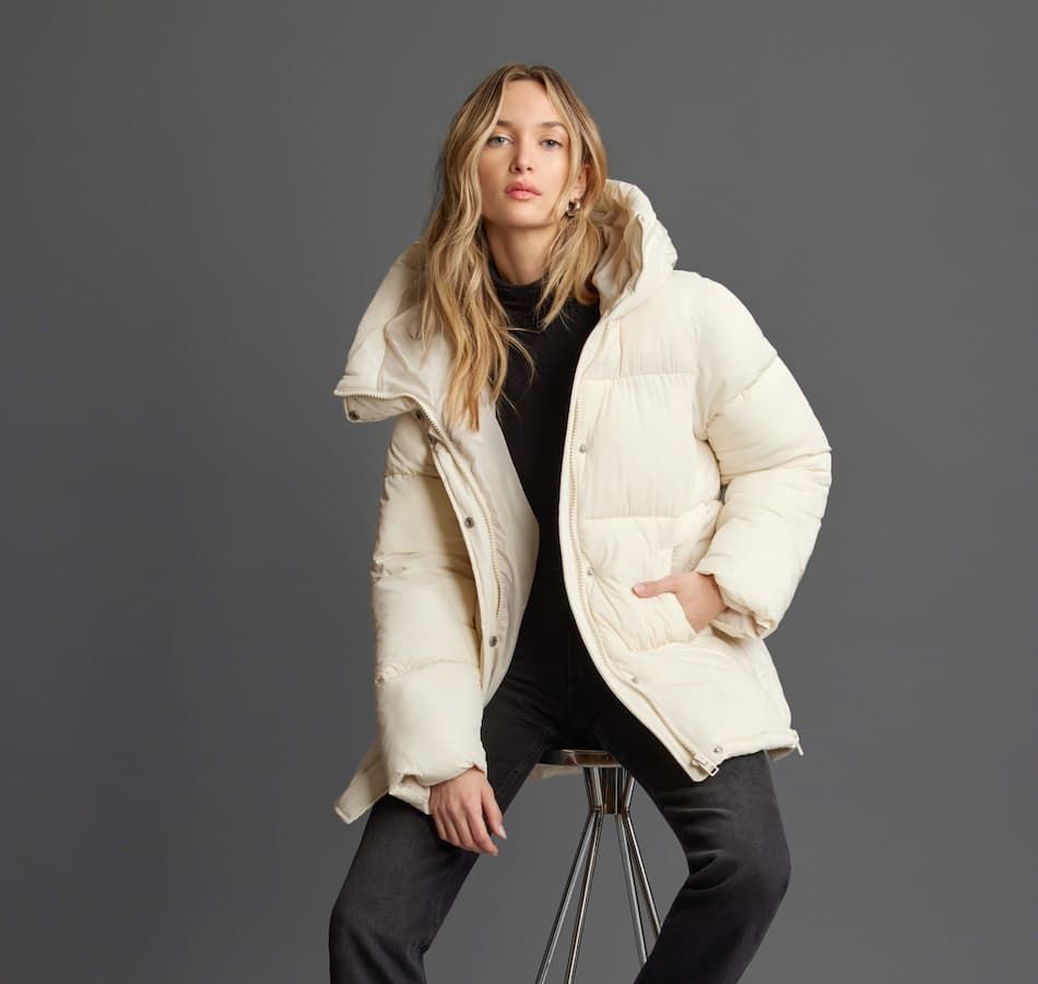 A model wears a beige puffer coat with black jeans and a black top.