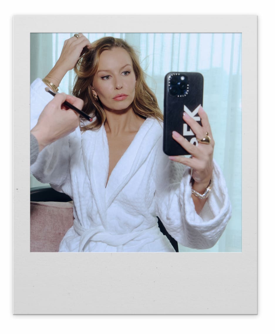 A blonde woman in a white blazer takes a selfie.