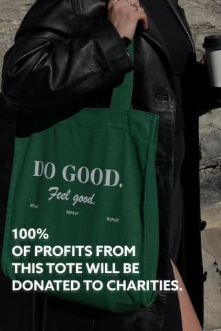 A girl wears the 'do good, feel good' tote bag while wearing a black trench coat.