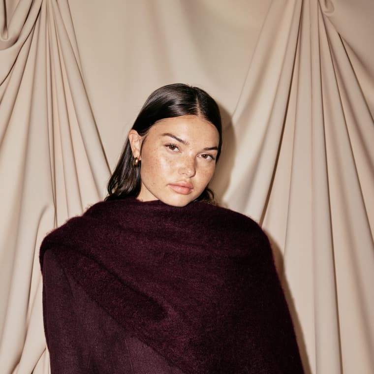 Model is wearing a burgundy coat and scarf.
