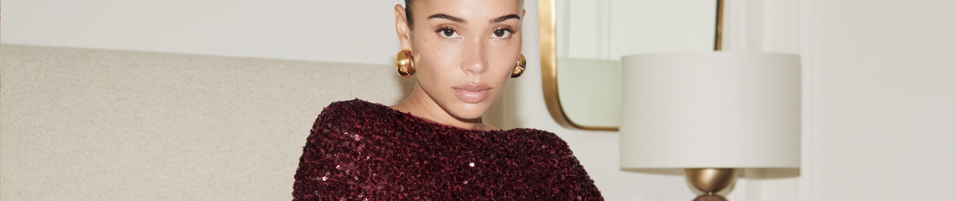 Model is wearing a burgundy sequin mini dress.