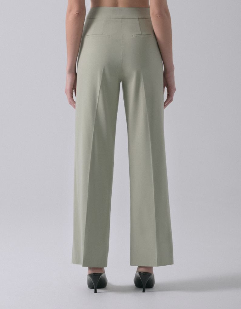 A model wears light khaki green straight leg pants. - back view.