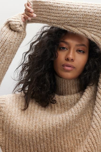 A model wears a beige knit sweater.