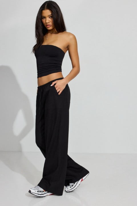 Model wears a black tube top and black sweatpants.