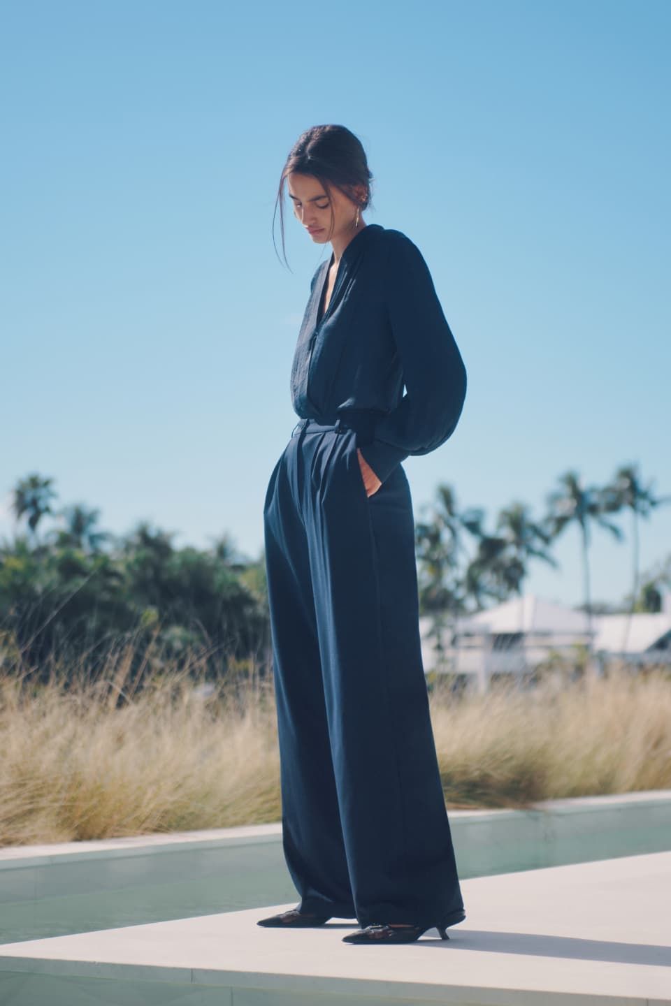 A model wears a navy blue blouse with navy blue wide leg pants.